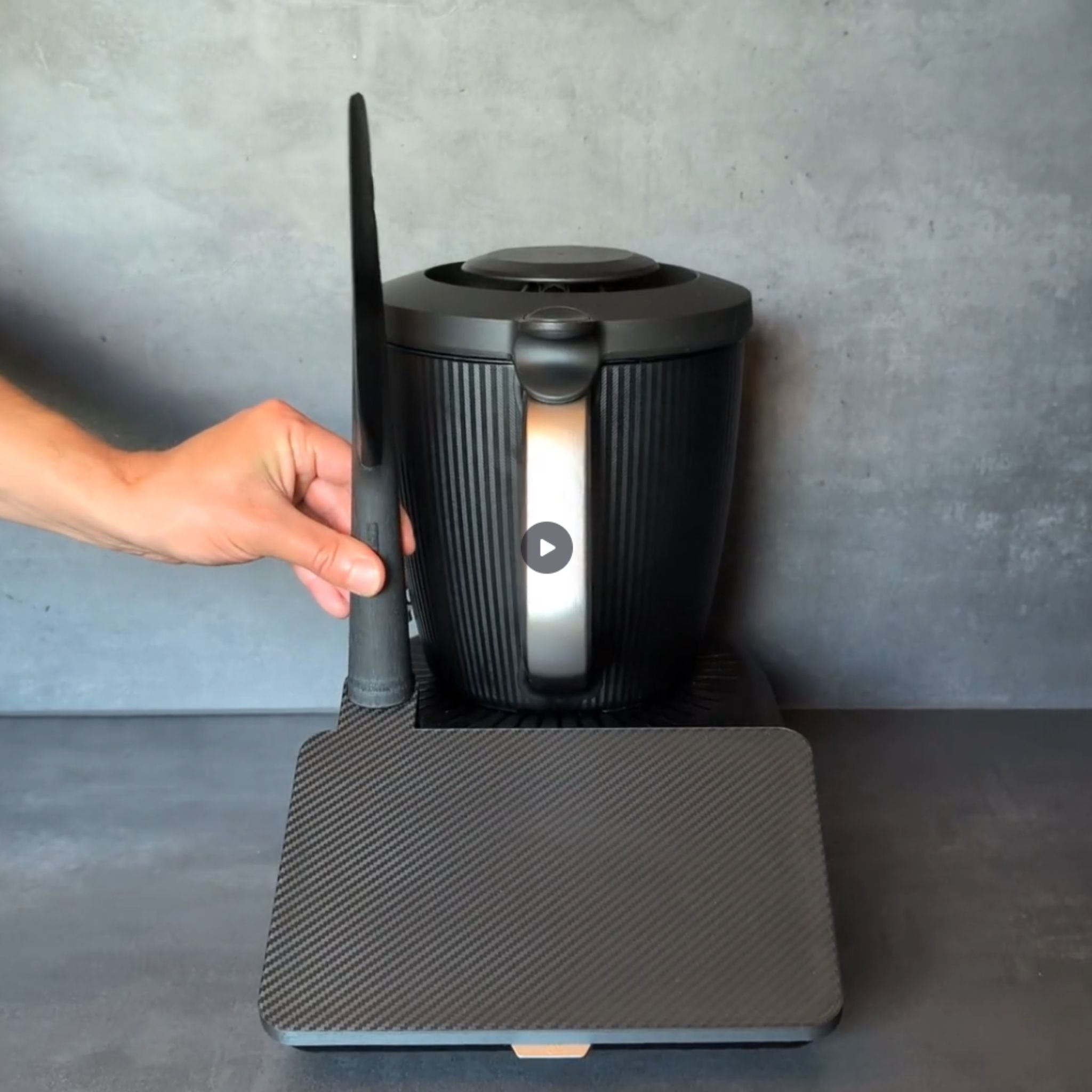 TM7 Displayschutz mit Wunschtext in Carbon-Optik. Gezeigt wird das Aufsetzen der Displayabdeckung auf den Thermomix TM7 sowie das Einsetzen des Spatels in den integrierten Spatelhalter.
